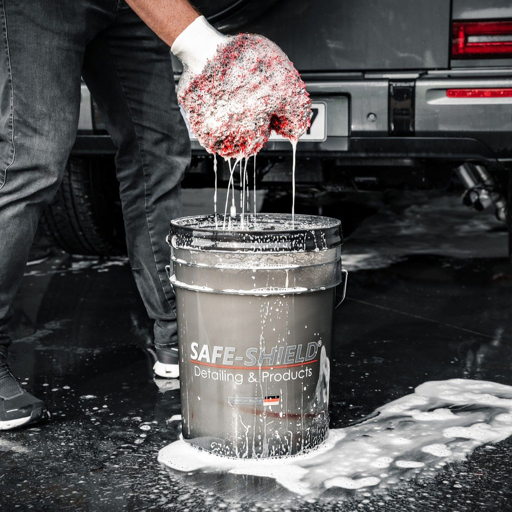 Black and red microfibre wash mitt holding shampoo solution above a Safe-Shield wash bucket